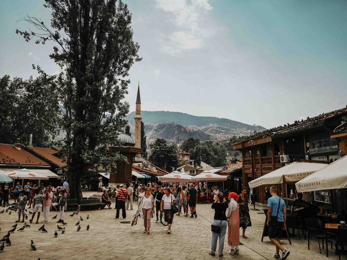 People stroll through Sarajevo. There is a minaret in the background.
