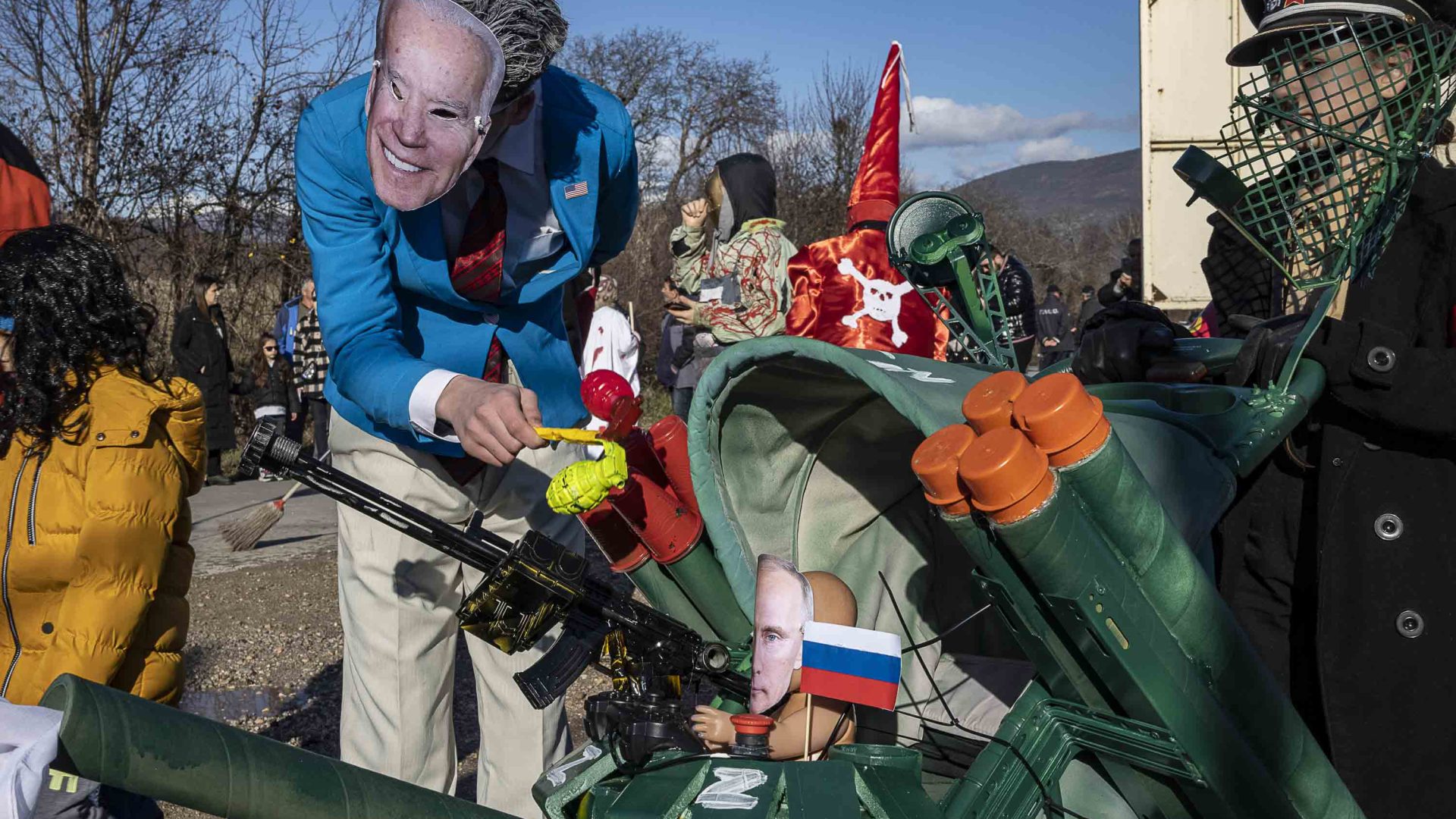 A man dressed as Joe Biden pushes a small Putin the his stroller.