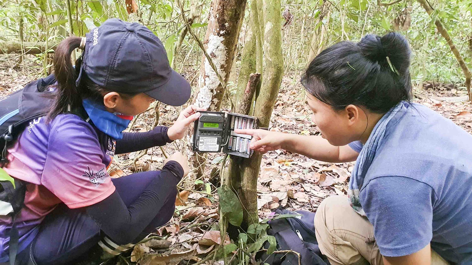 Two women operating a camera trap.