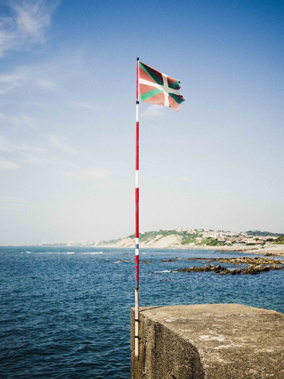 A basque flag by some water.