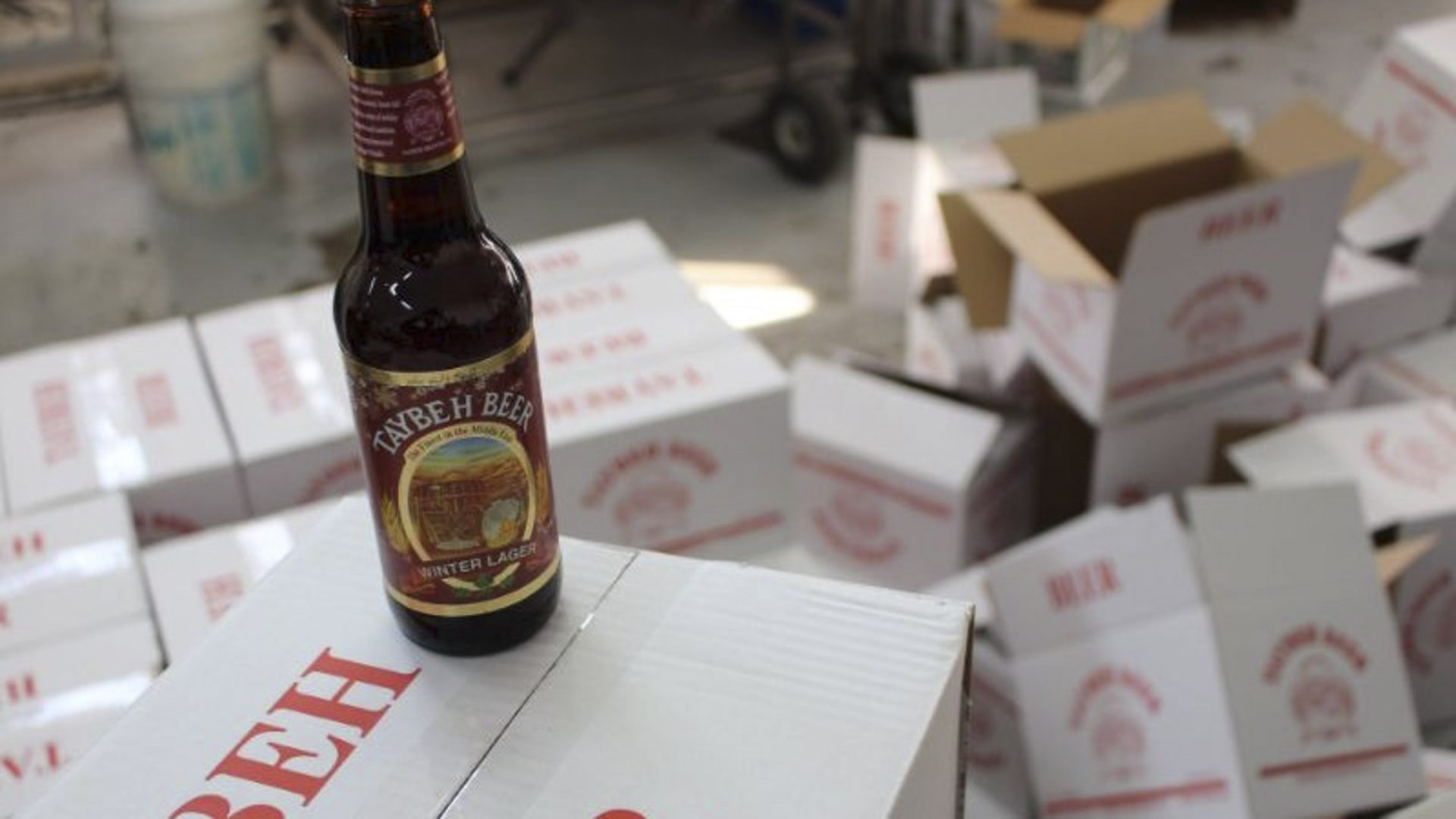 A bottle of beer stands on some boxes containing beer.