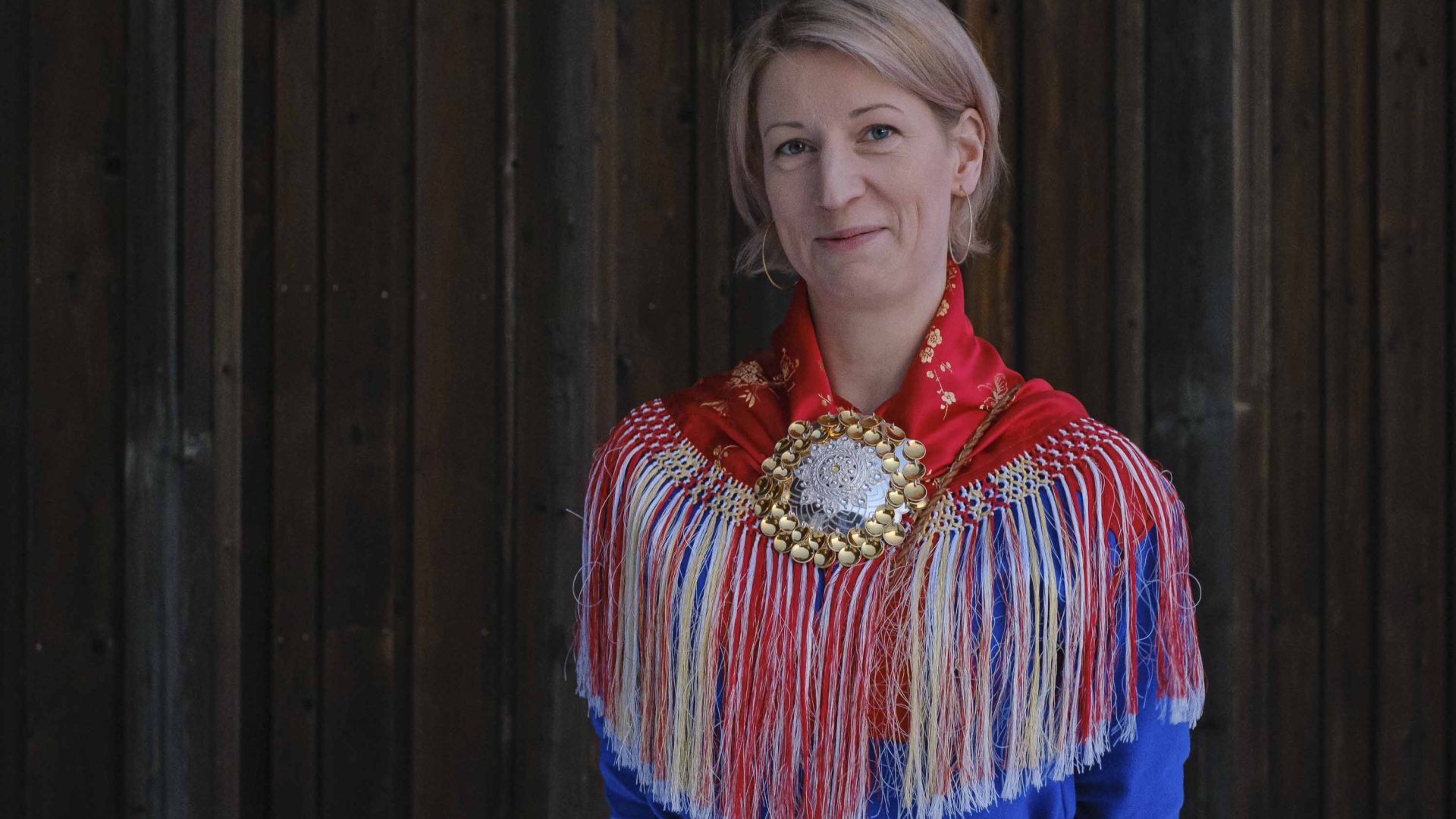 A blonde woman in traditional red, white and blue Sapmi clothing.