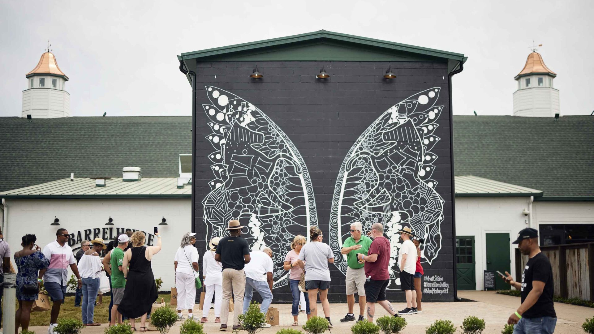 A group of people stand in front of a black and white mural.
