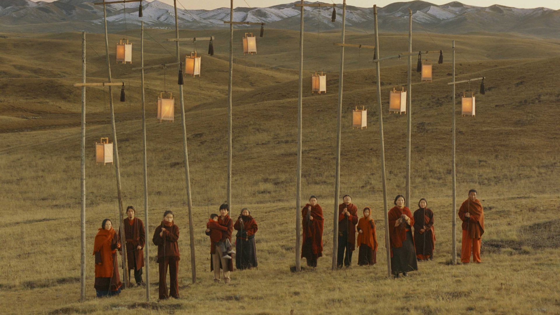 Nomads wearing red and holding lanterns on a hill.