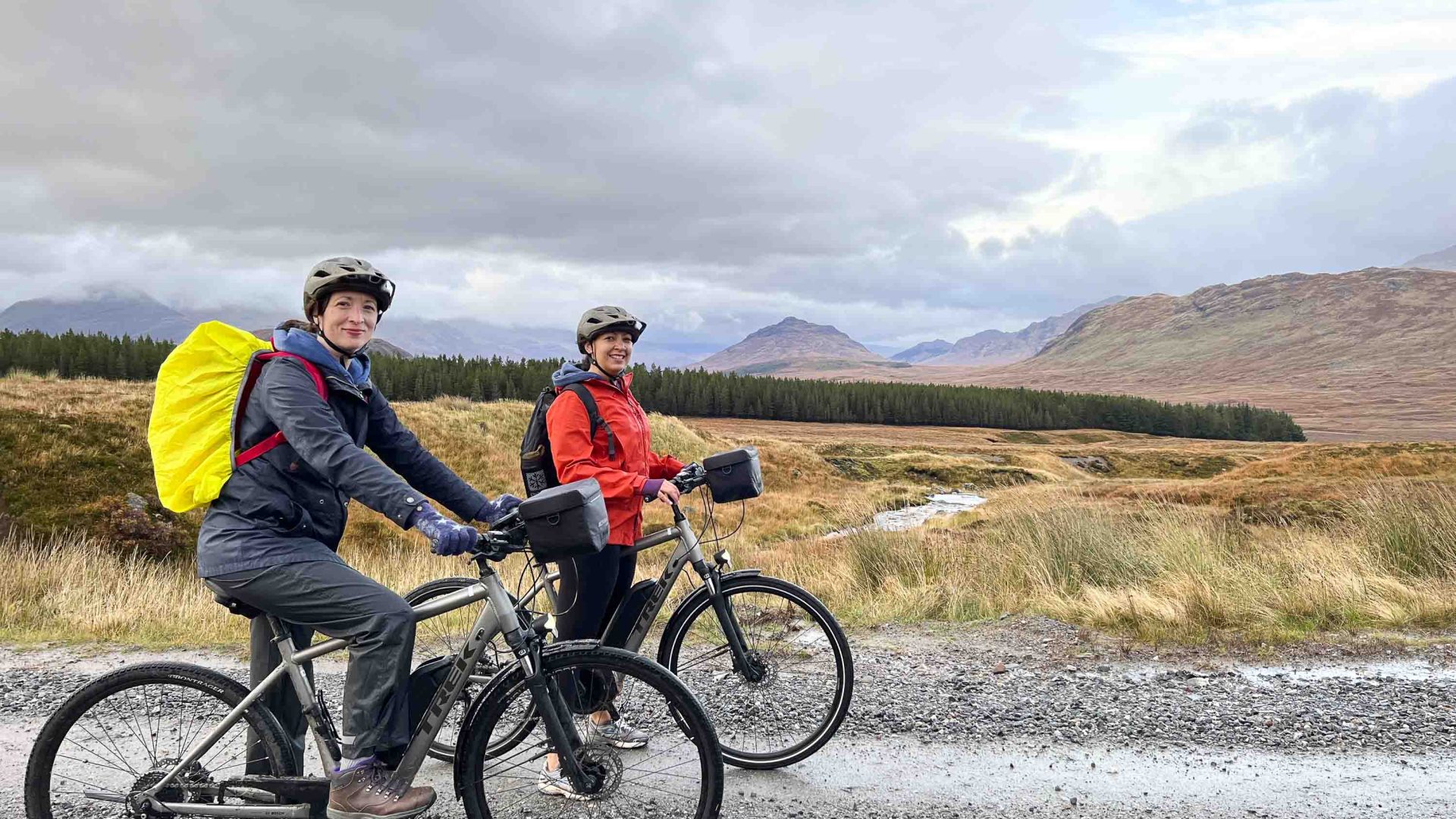 Two women on e bikes in front of mountains.