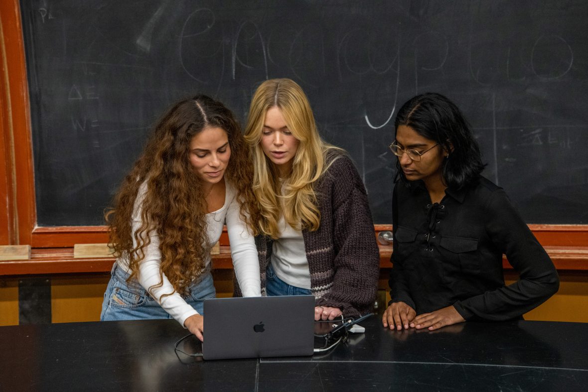 Sage Lenier and two other Berkeley students stand around a laptop, reading the screen.