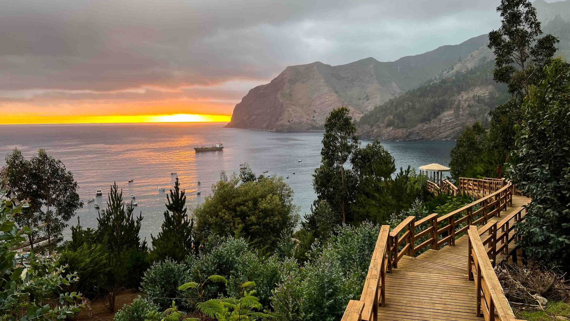 A wooden boardwalk leads to the sun rise over the water on Robinson Crusoe Island.