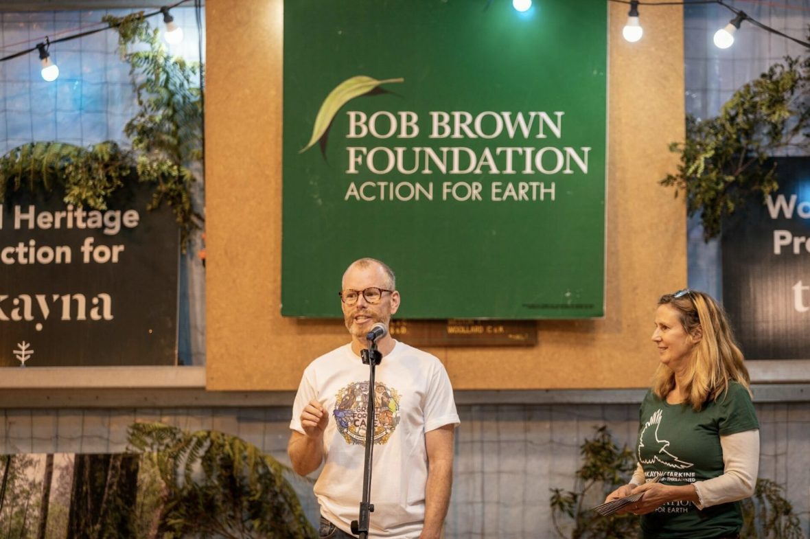A man stands at a microphone and addresses a crowd of people during a presentation at the Bob Brown Foundation in Australia.