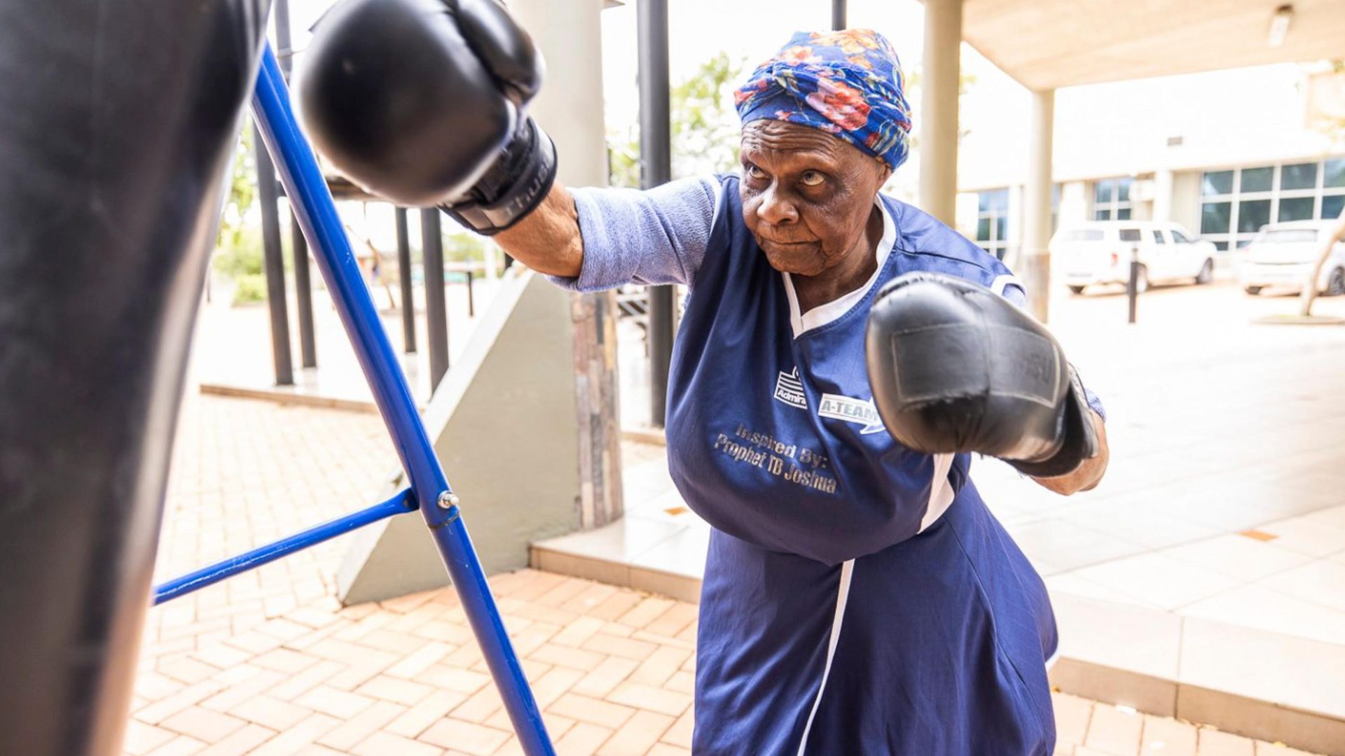 Constance Ngubane boxing in the air. She wears a blue tunic.