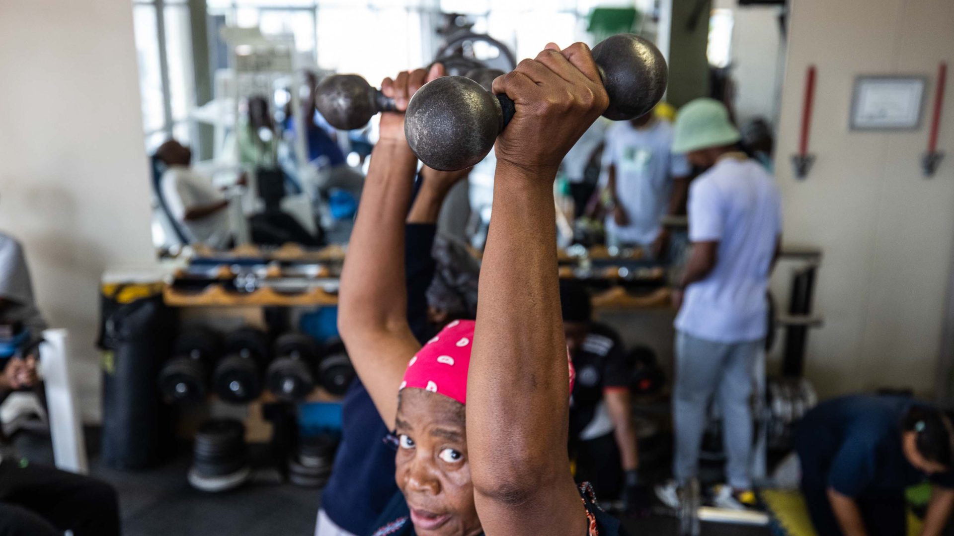 A boxing granny raises some dumbbells above her head.