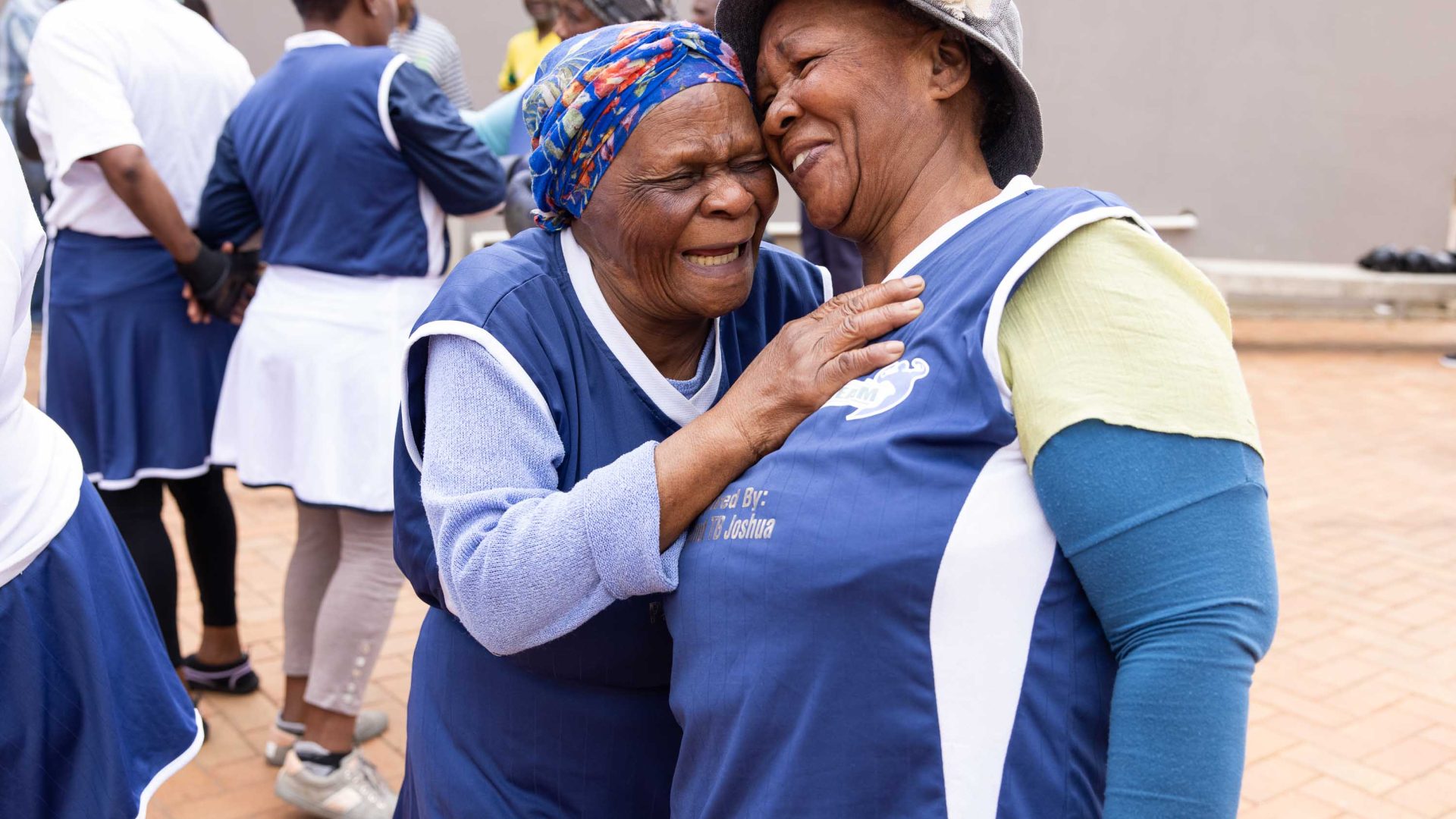 Two boxing grannies hug and smile together.