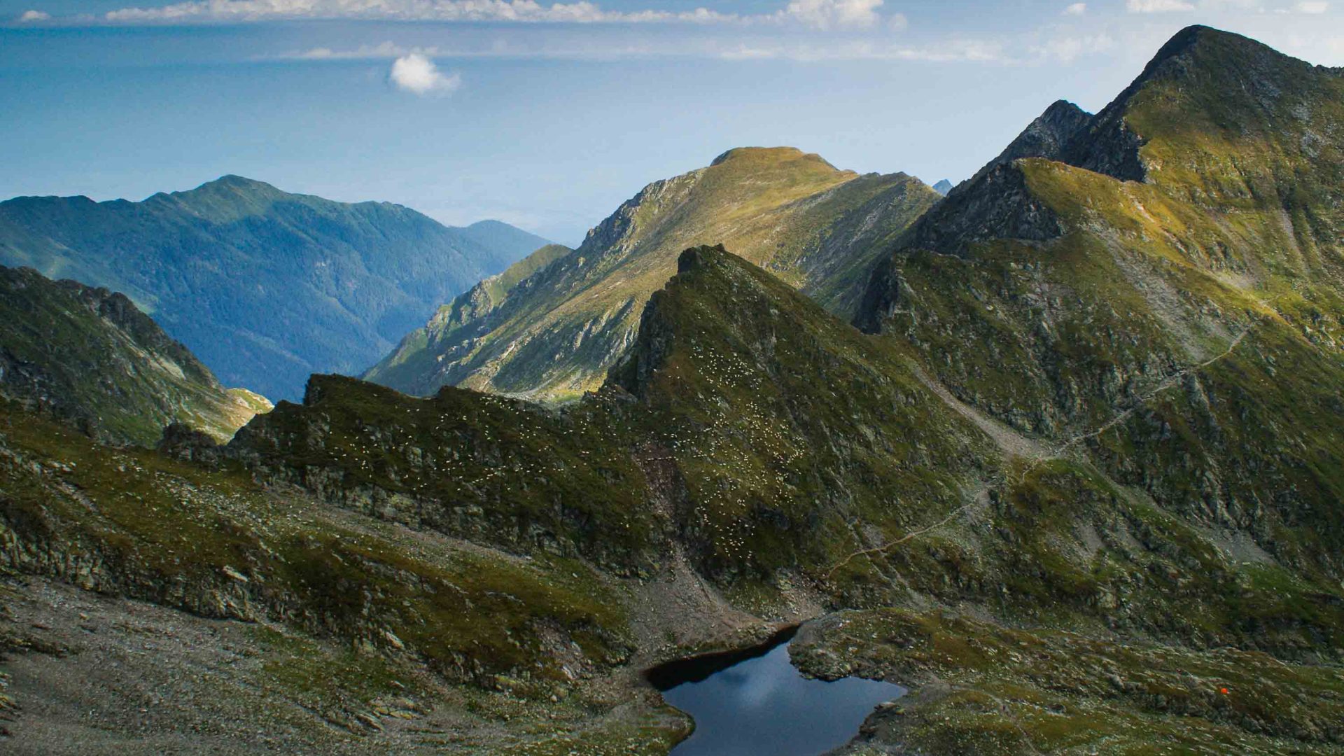 A panoramic view of mountains and valley leading to a lake.