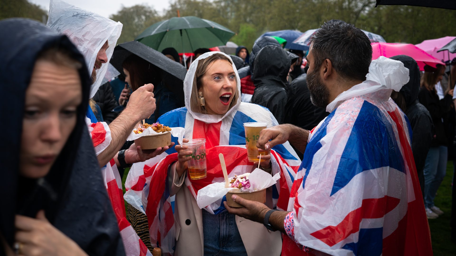 Three friends in Union Jack capes enjoy a beer and some food during the event.