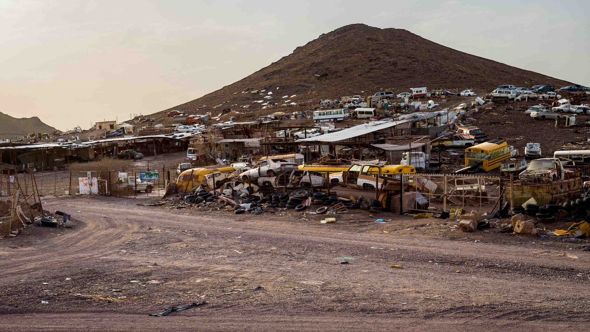 Abandoned cars piled up in a desert landscape.