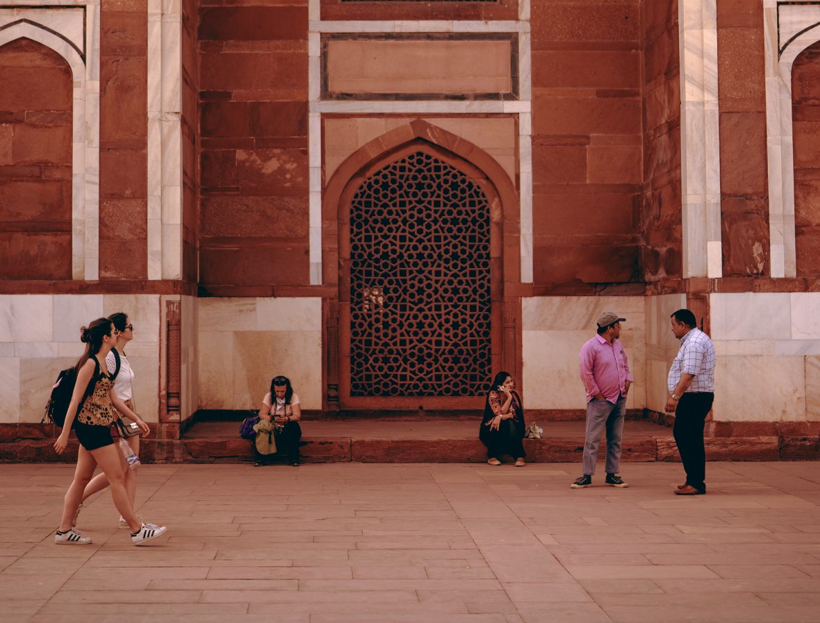 Tourists walk past locals seated near Humayun’s Tomb in New Delhi, India.
