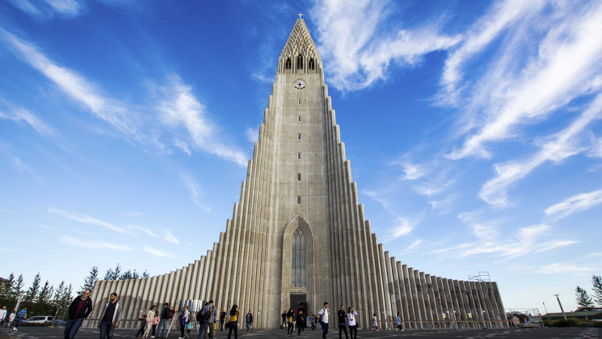 People stand at the base of Hallgrímskirkja, a tall Lutheran church.