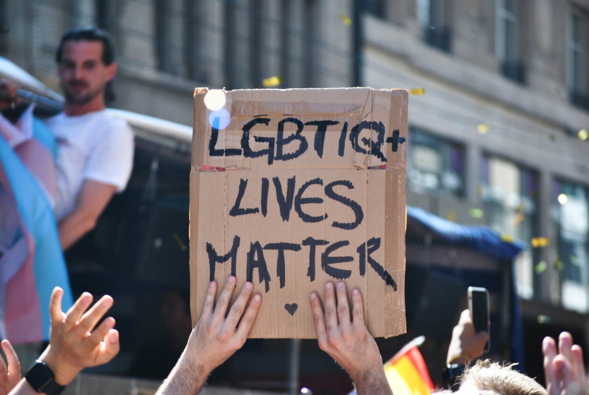 Hands hold up a sign that says LGBTQ+ lives matter.