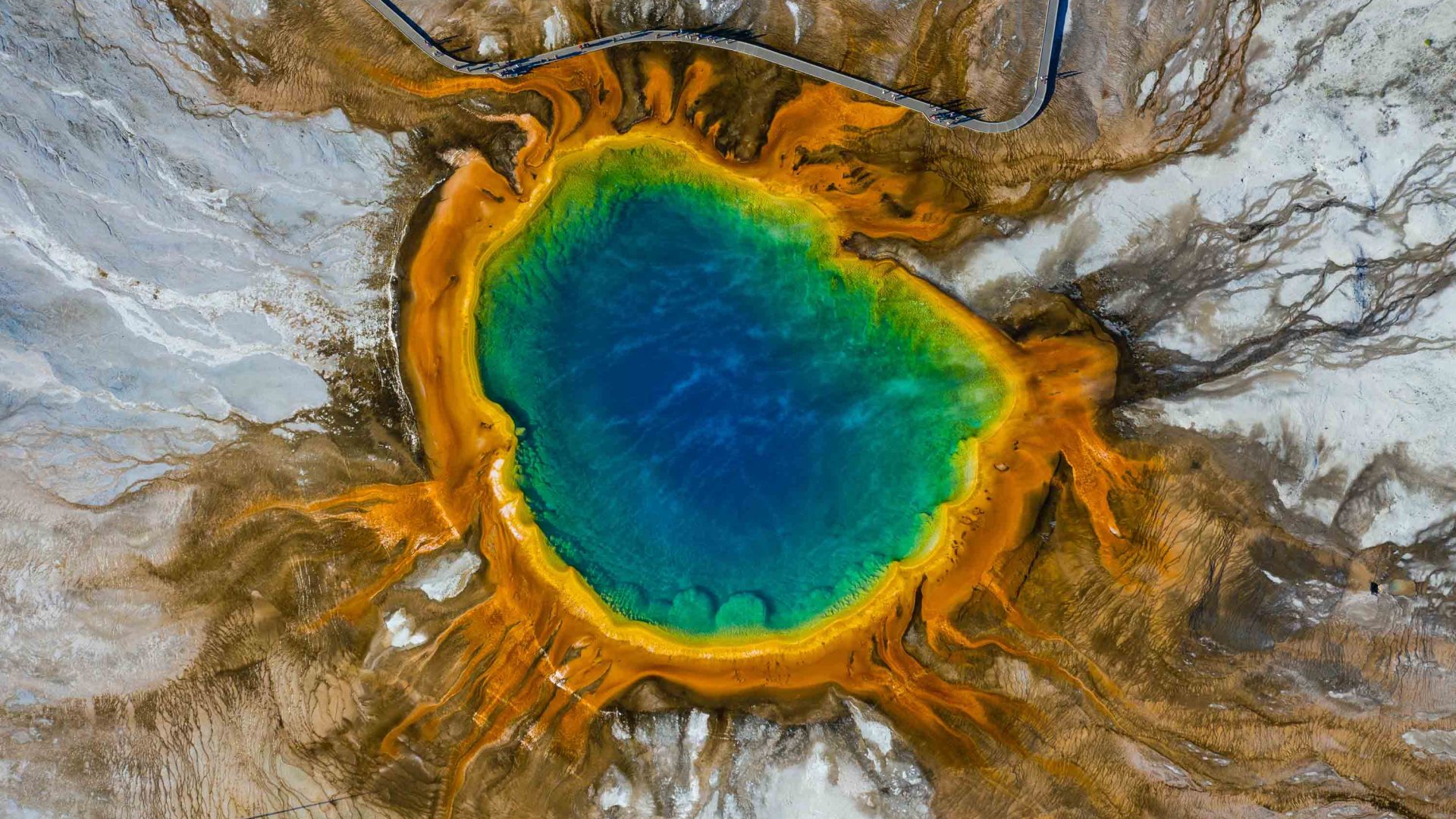 An aerial view of a blue, yellow and orange natural pool at Yellowstone.