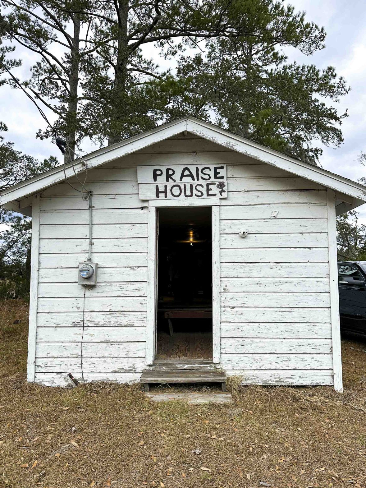 A white wooden hall with the words 'Praise House' painted above the door.