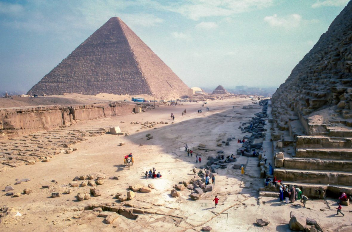 An aerial view over the pyramids with the small figures of people walking around the structures.