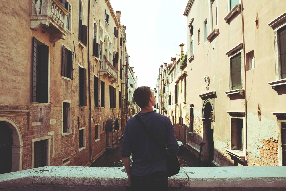 A traveler looks out at buildings in Venice.