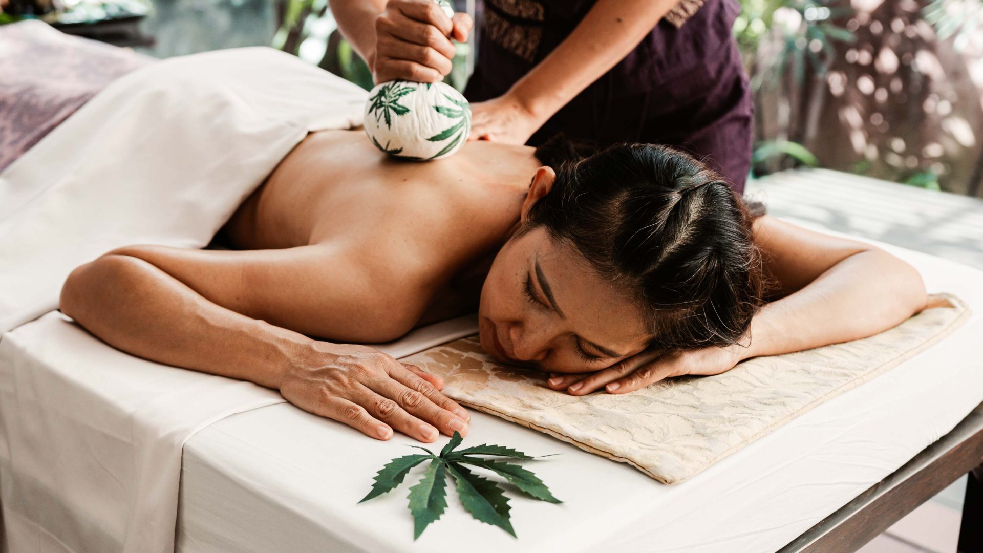 A woman gets a cannabis treatment on her back.