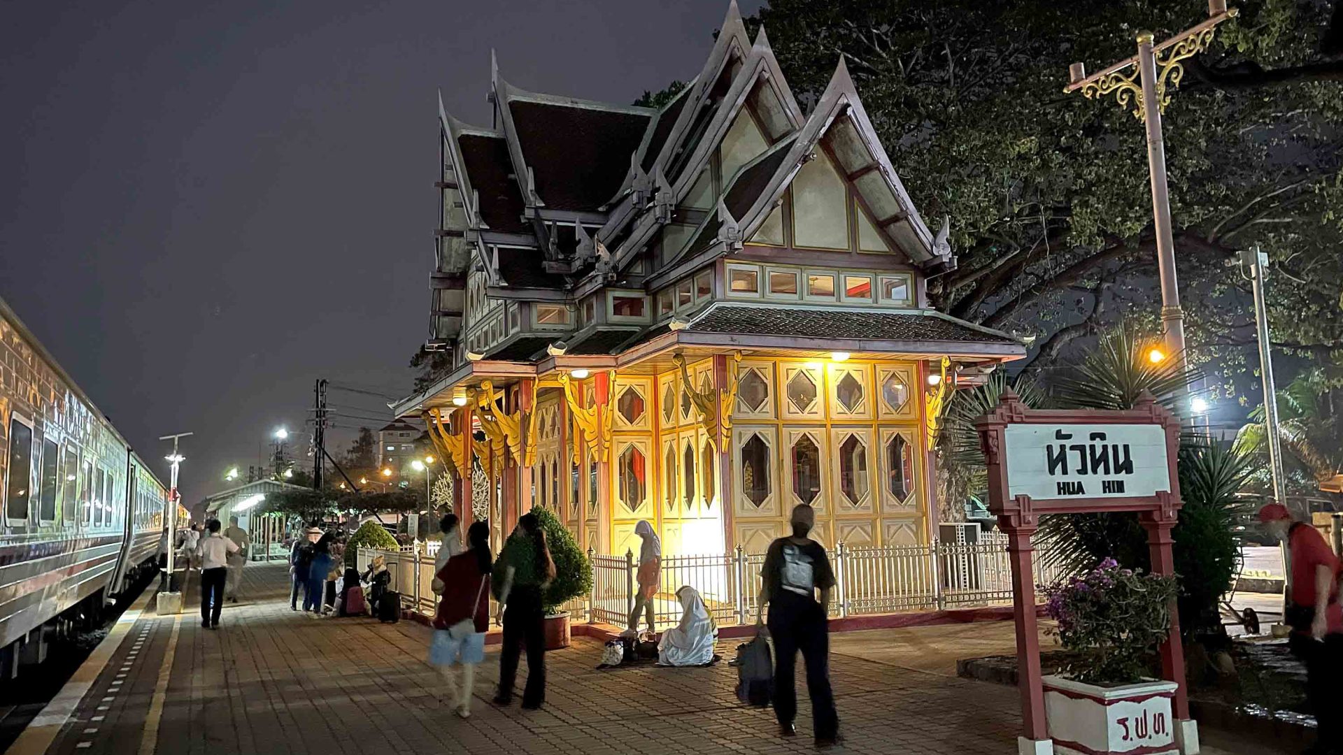 Express 31 at Hua Hin station at night. The station is lit up and people walk along the platform.