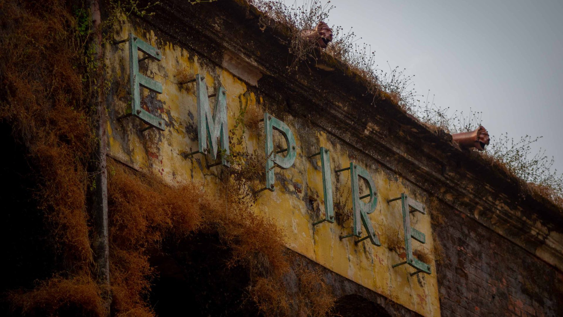An old cinema sign that says Empire has plants growing over it.