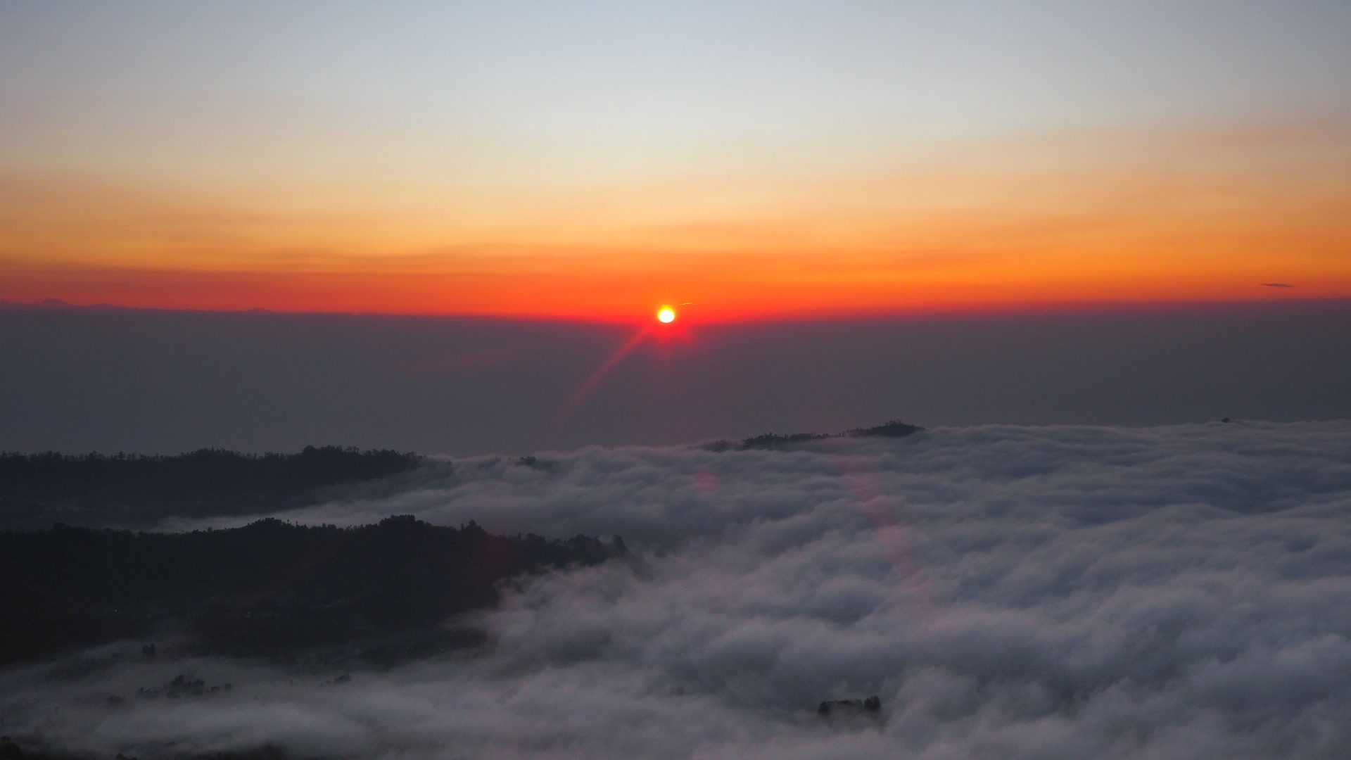 The sun rises over a sea of cloud.