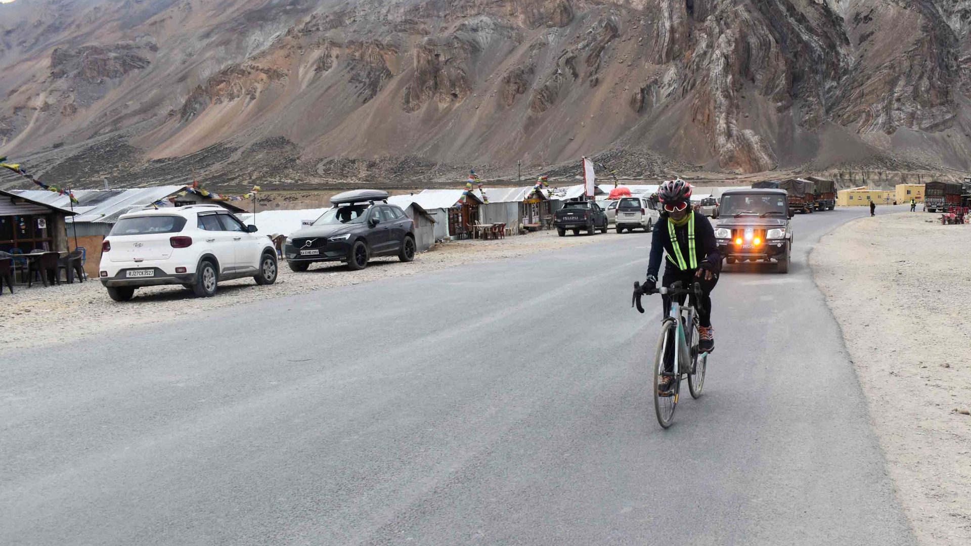 Preeti cycling past cars and arid mountains.