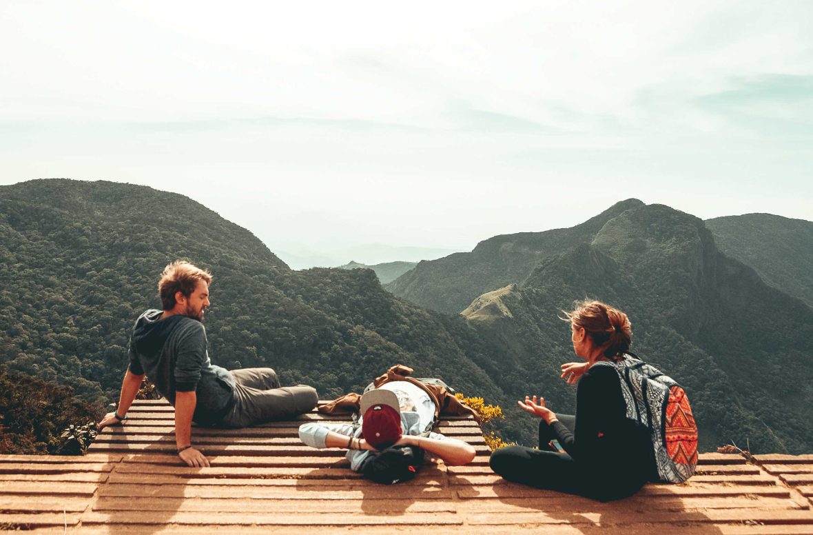 Friends on holiday talk overlooking views of mountains.