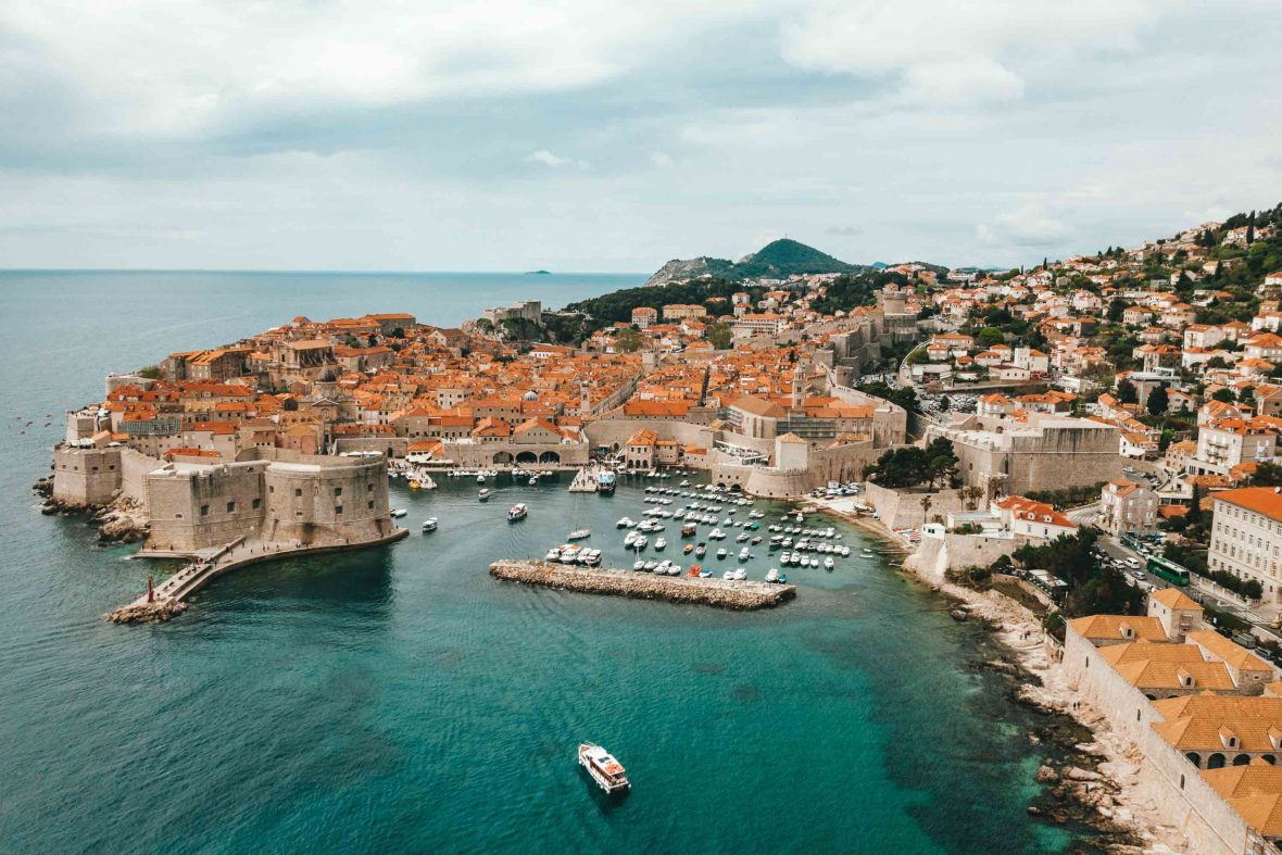An aerial view over brown buildings and blue harbour of Dubrovnik.