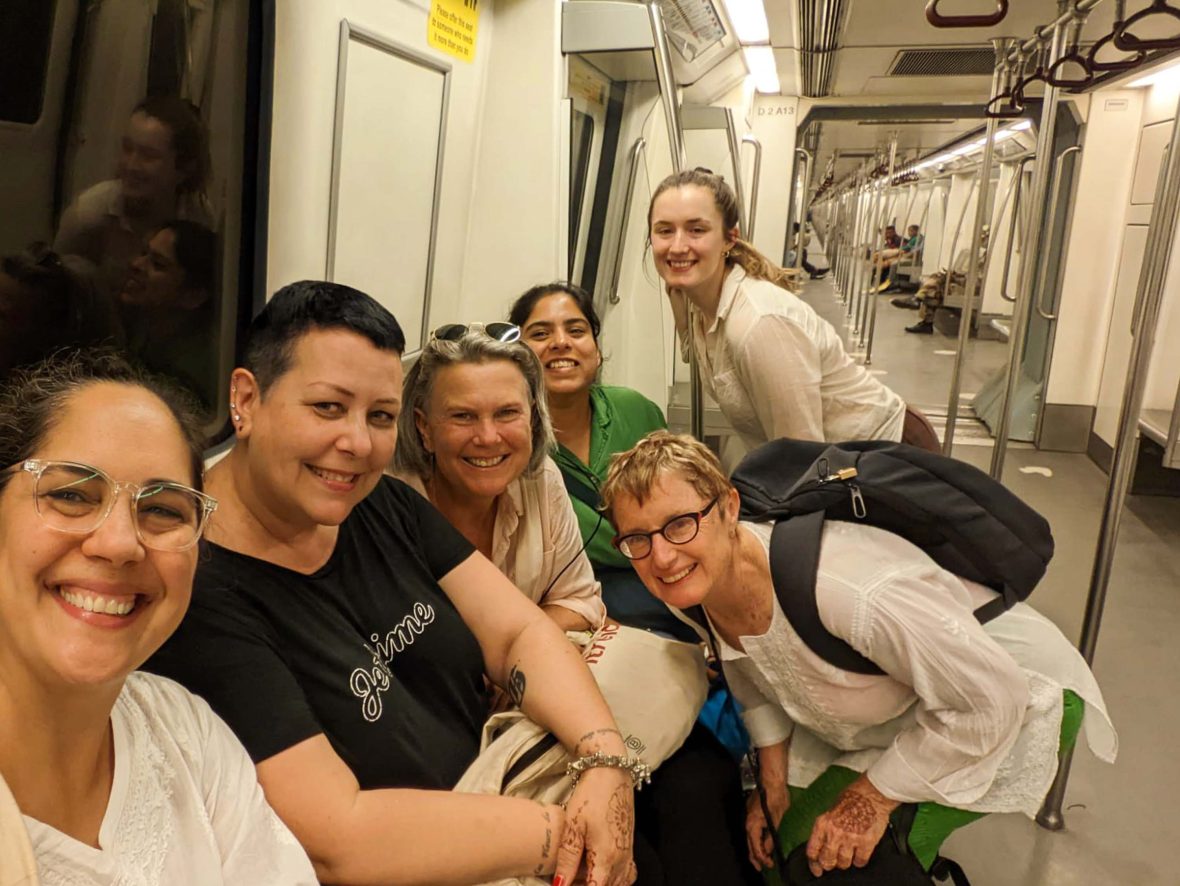 A group of women smile for a group picture on the metro.