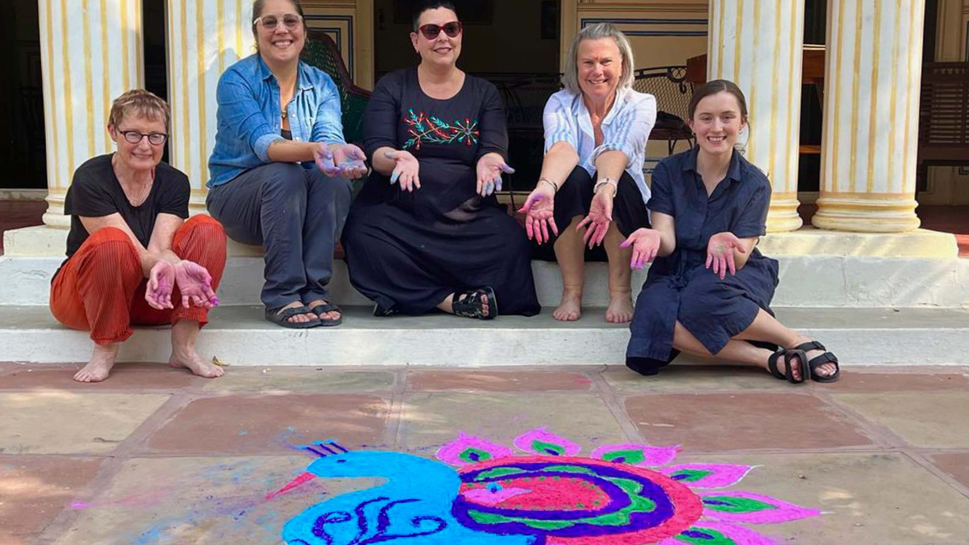 The group smile for a photo in front of a rangoli during Diwali.