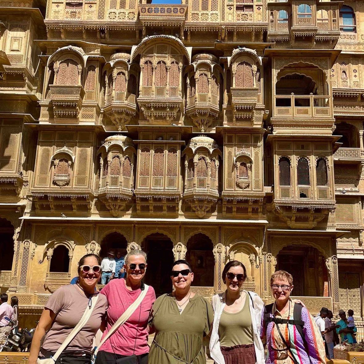 A group of women smile in front of an ornate building.