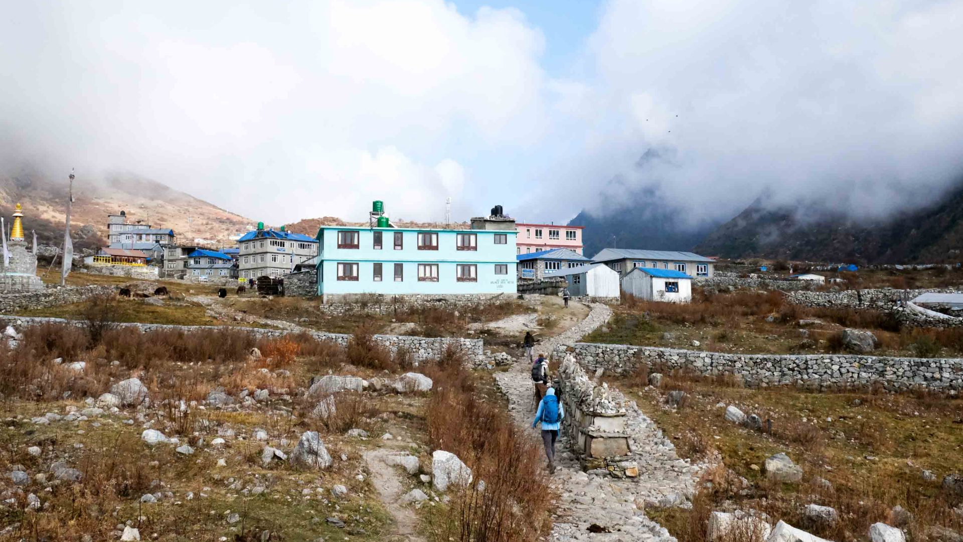 Hikers walk up to the coloured houses in the village.