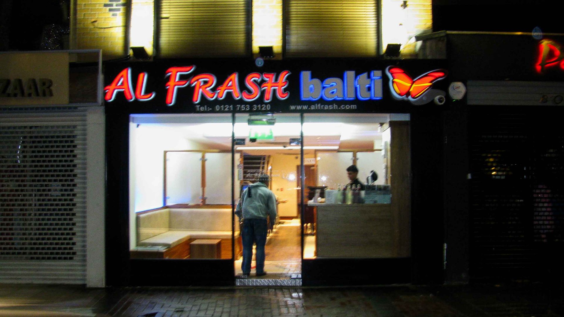 A shop front at night that sells Balti.