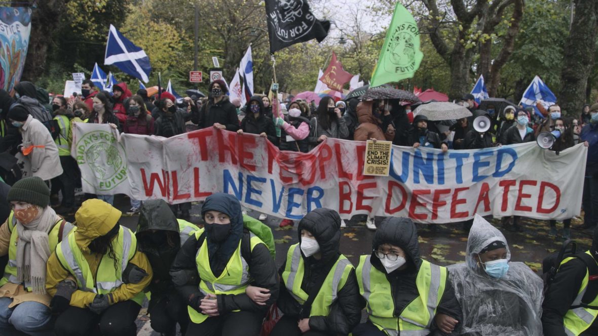 Protesters in Glasgow hold up a sign that reads "The people united will never be defeated".