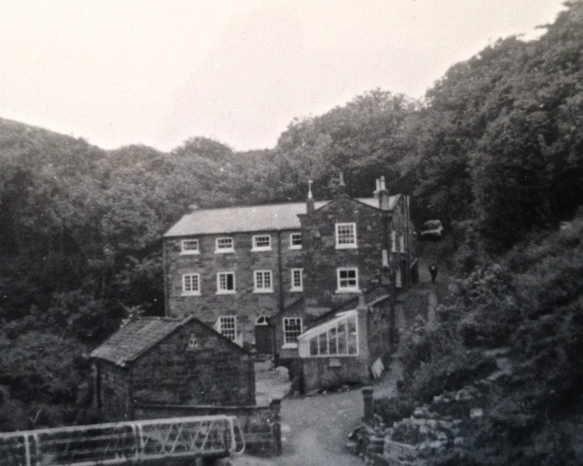 A black and white photo of a big youth hostel nestled in trees.