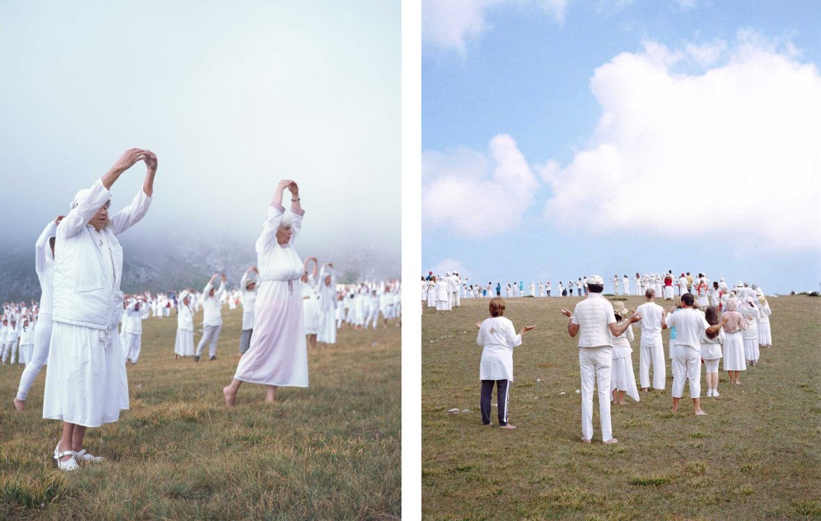 People dressed in white dance on a green hill.