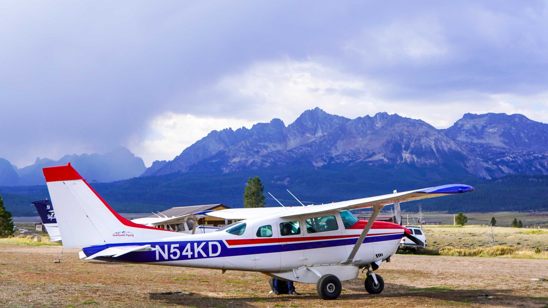 A small plane against a backdrop of tall mountains.