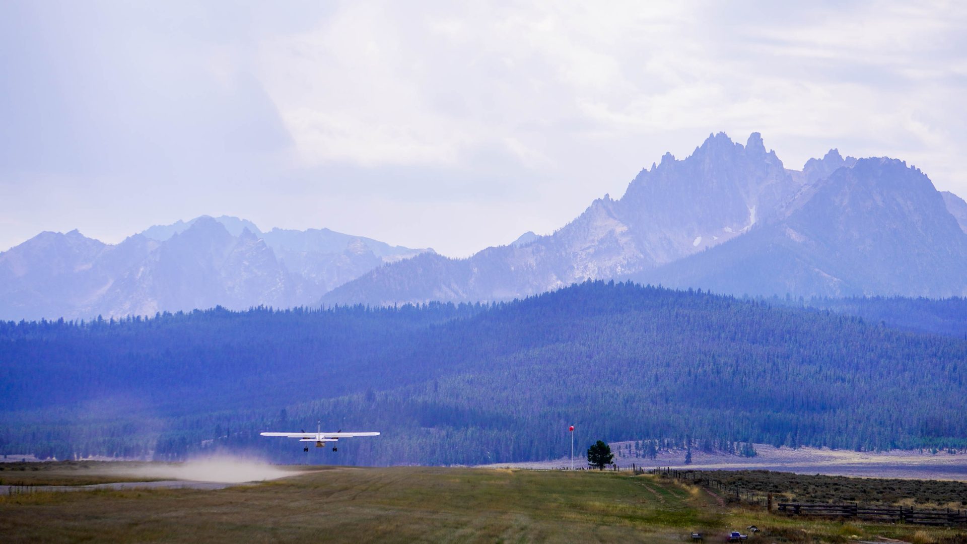 A plane takes off against a backdrop of mountains.