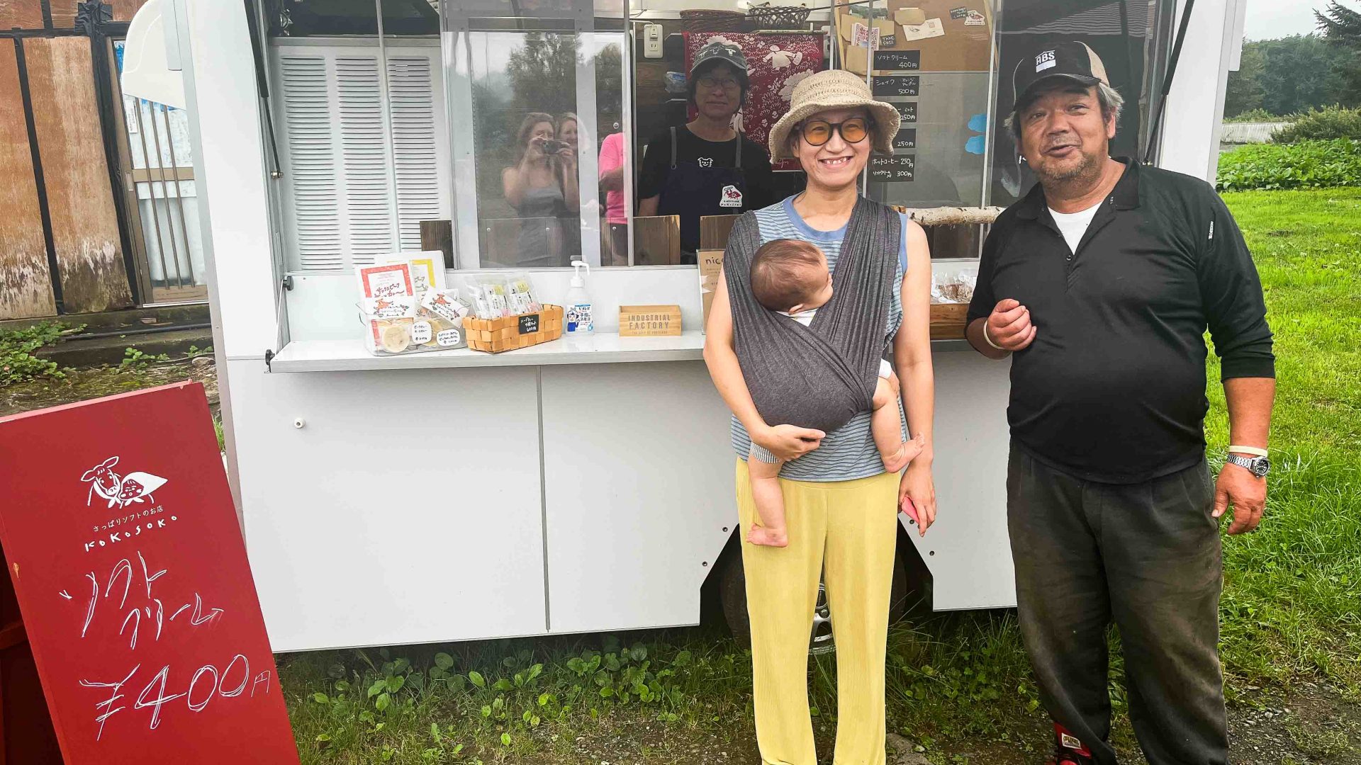 A woman, man and baby stand in front of a food truck.