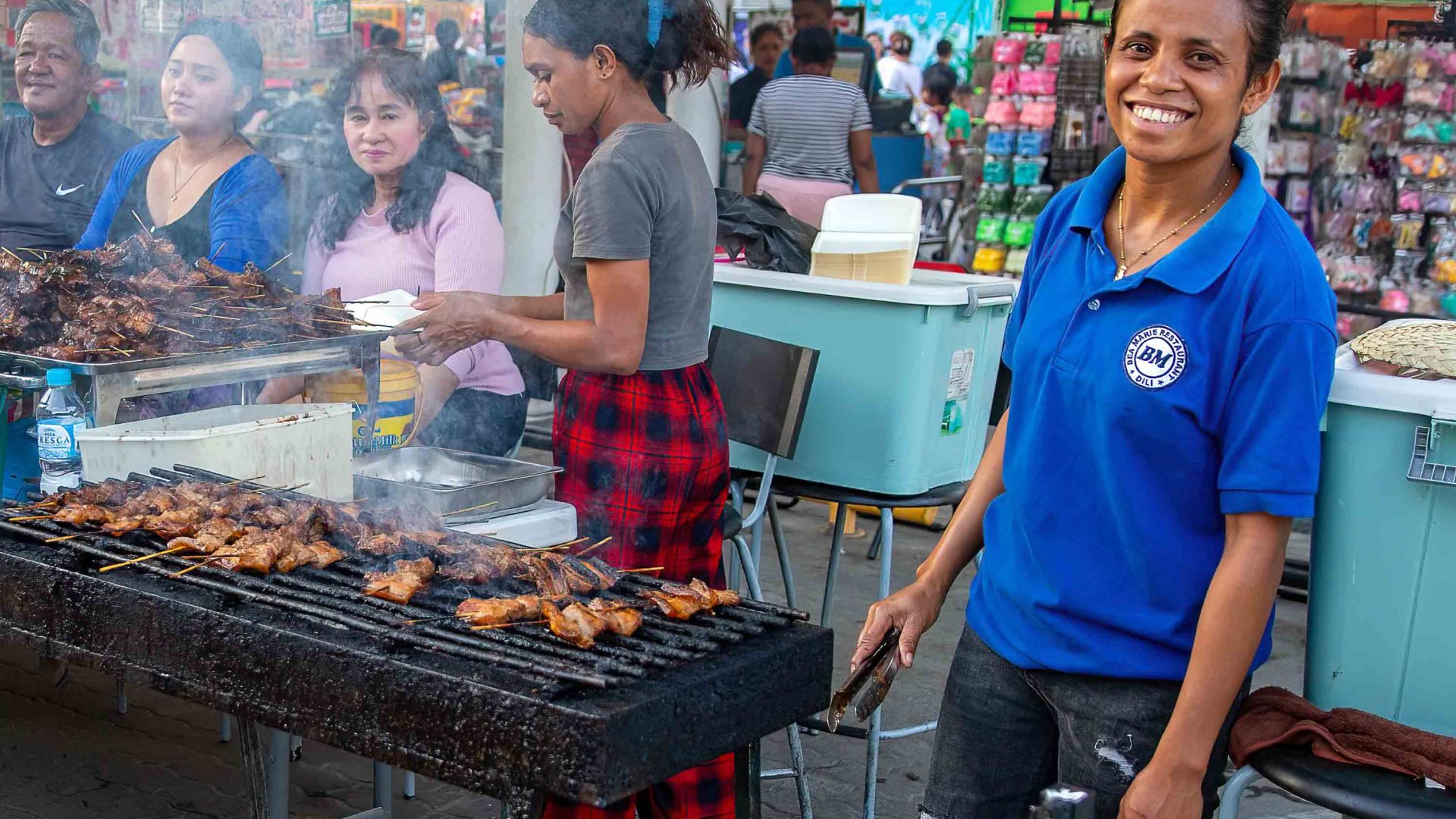 A man smiles as he BBQ's satay chicken at Timor Plaza night market.
