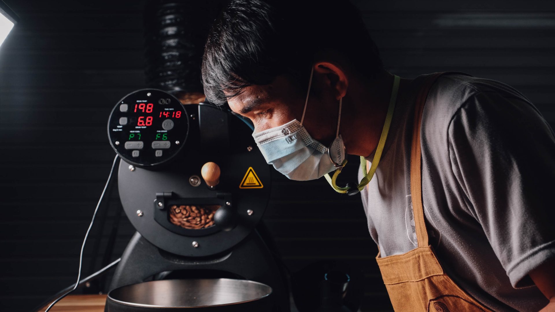 A man looks at the coffee grounds coming out of a coffee machine in Vientiane.