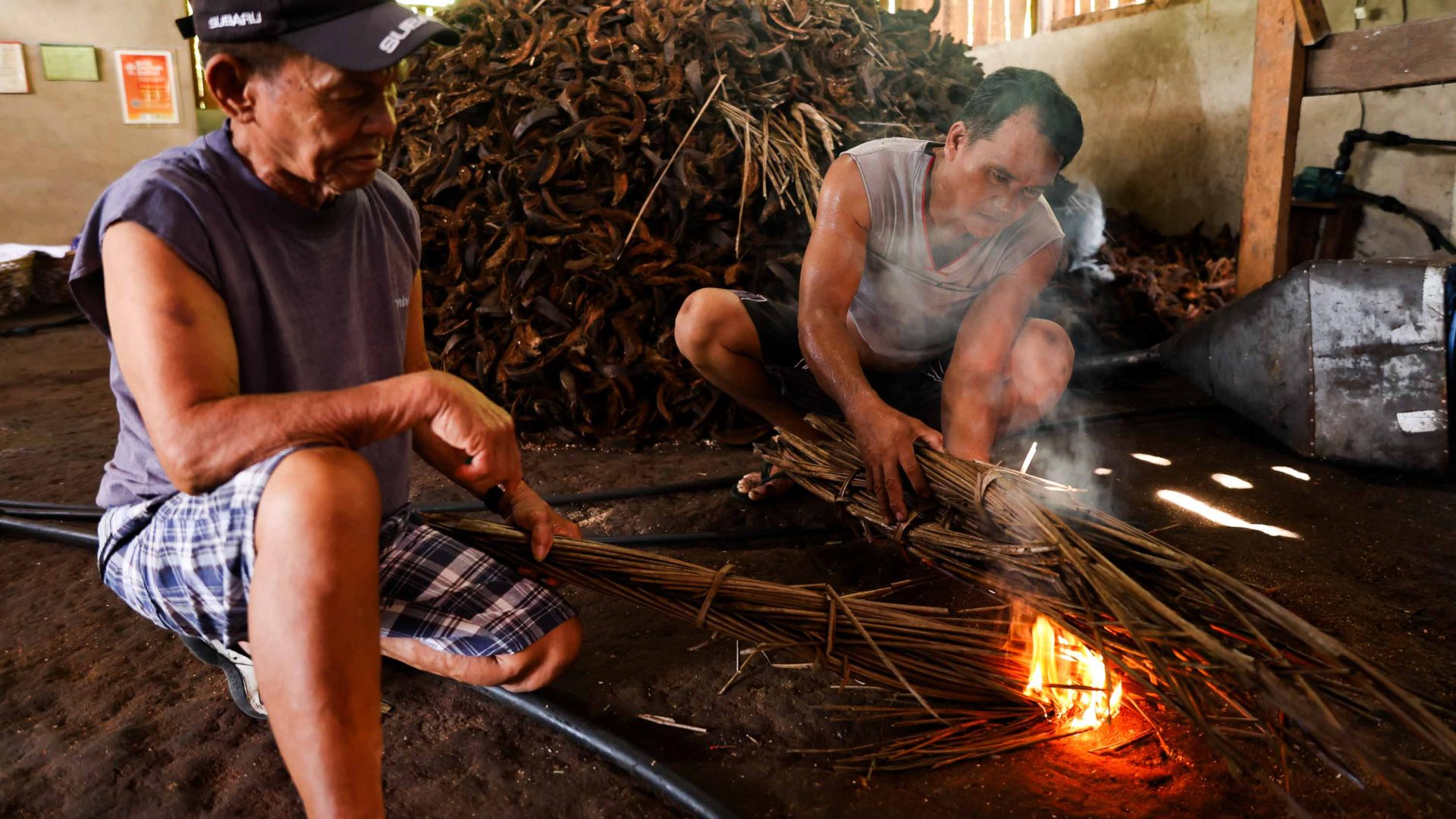Coconut husks are burned by two men.