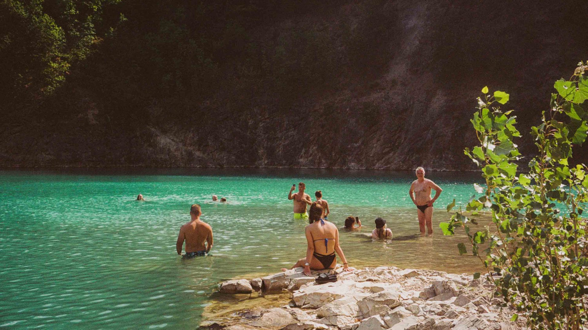 People swim at a lake in At Fruška Gora, an expansive national park. The water is a turquoise colour.