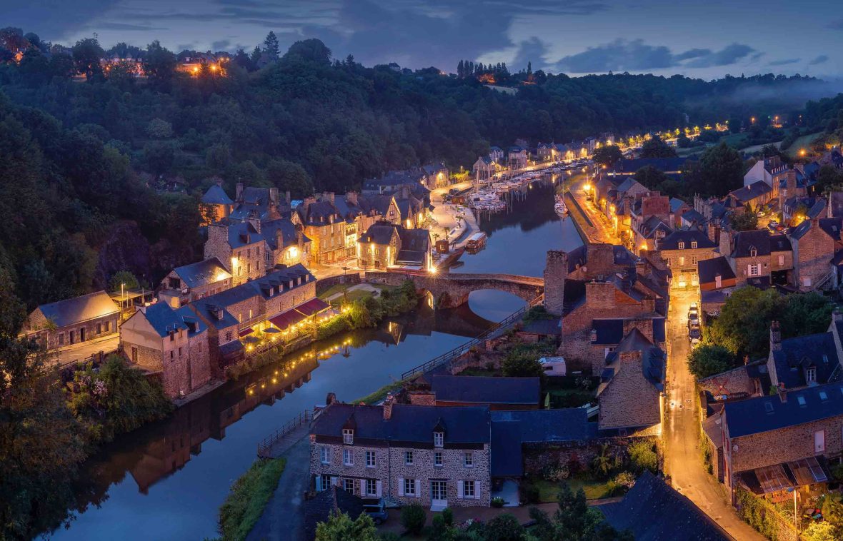 A town on a river lit up by lights in homes at night.