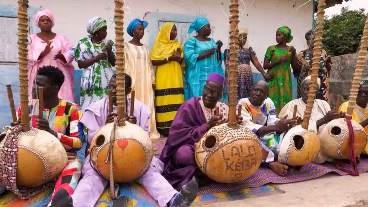 Several people play the kora together in a performance.