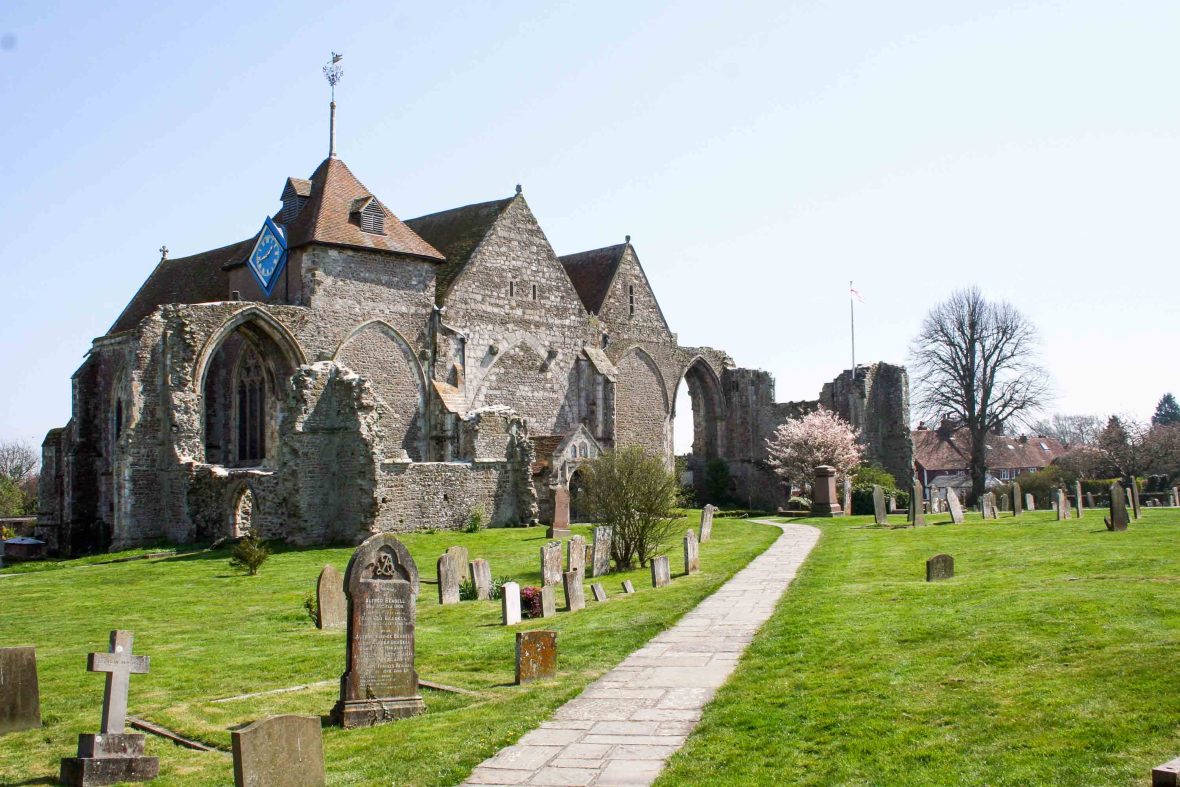 An old grey stone church surrounded by a graveyard.